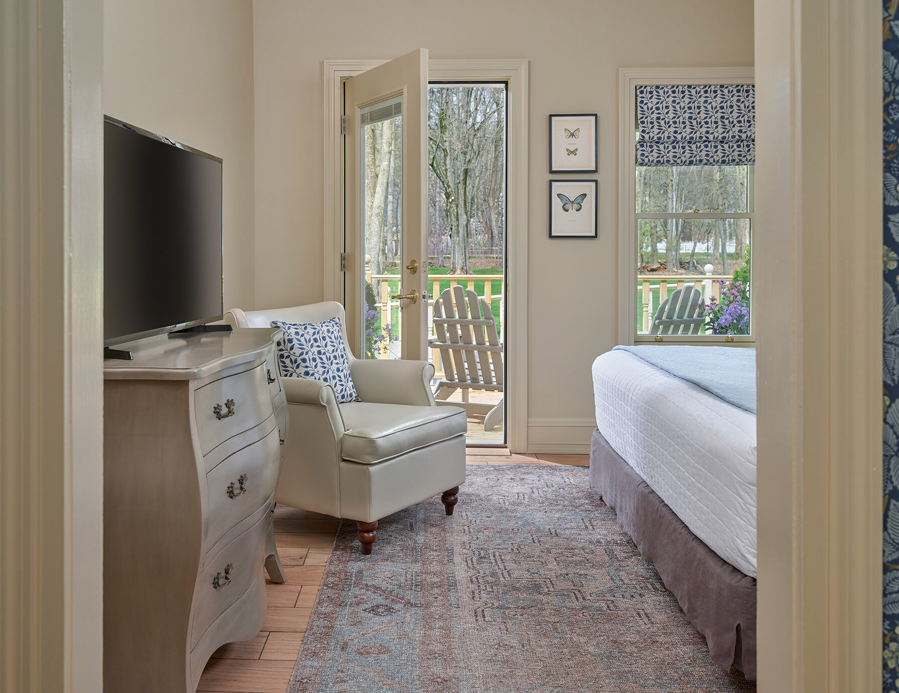 Plush red chair next to table with wine glasses and glass doors looking out on a Cooperstown Bed and Breakfast